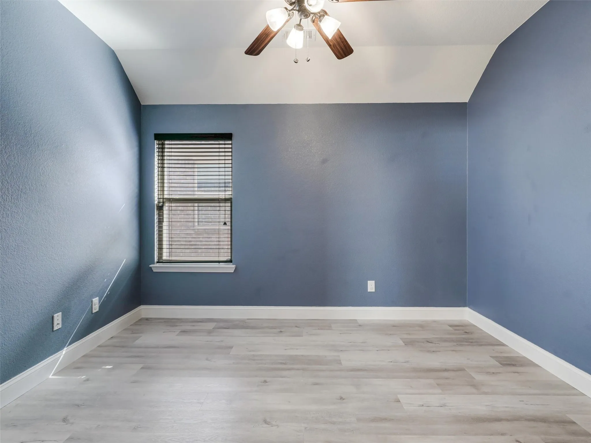Vaulted ceilings, wood-finish flooring, ceiling fan, window with blinds, and white trim