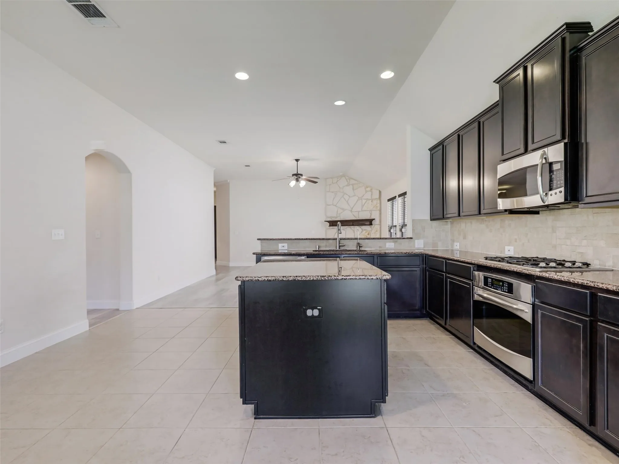 Kitchen featuring dark cabinetry, stainless steel appliances, granite countertops, and an integrated kitchen island
