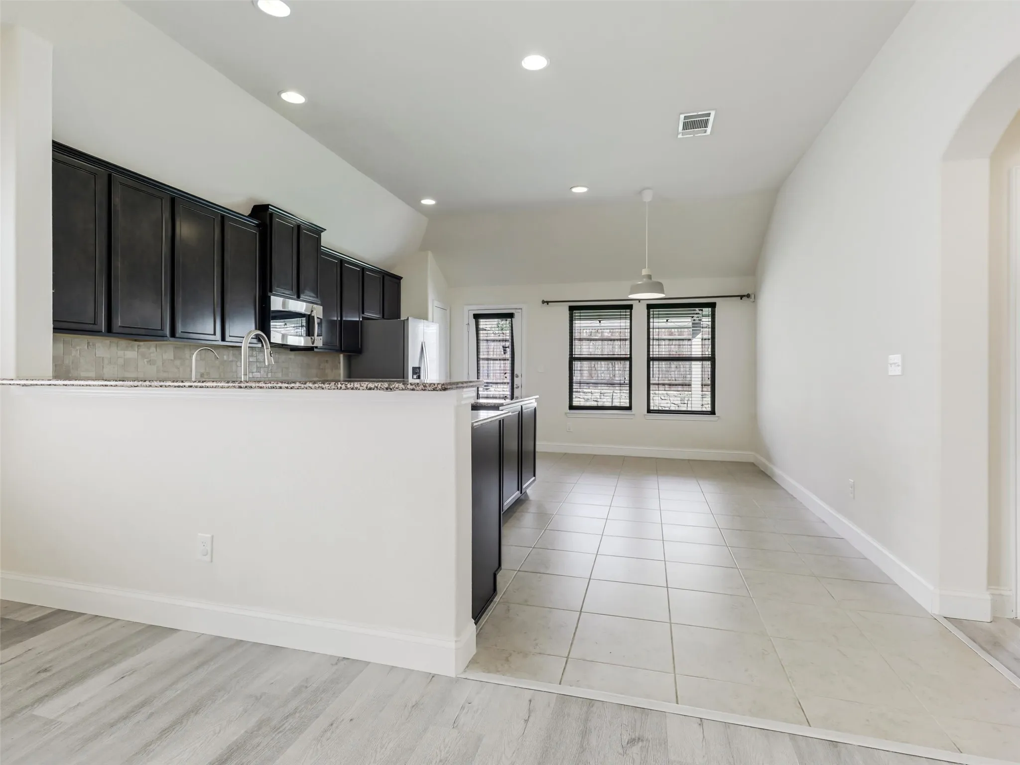 Kitchen with dark wood-finish cabinetry, stainless steel appliances, and a mosaic tile backsplash