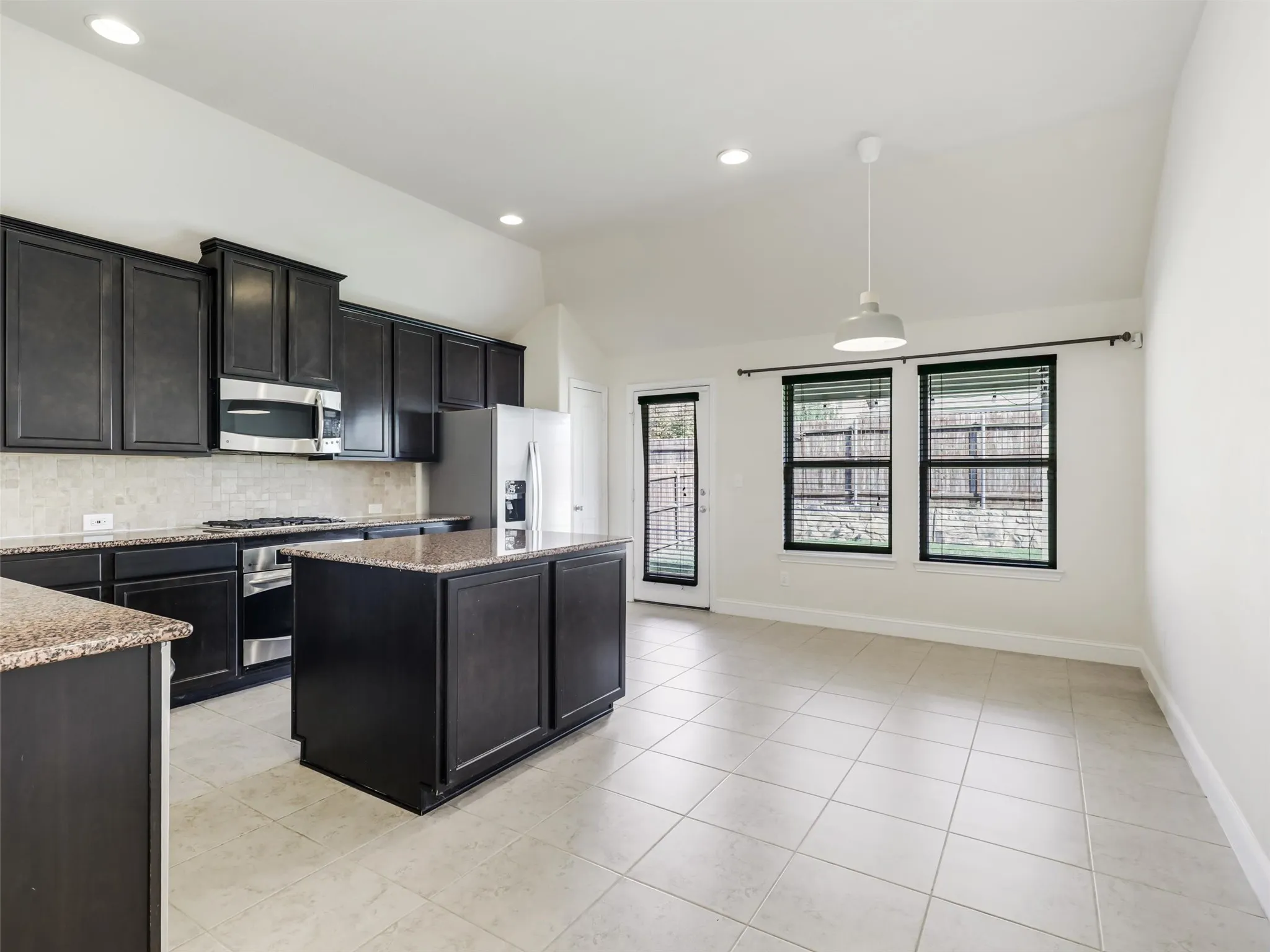 Kitchen with dark wood-finish cabinetry, granite countertops, and stainless steel appliances