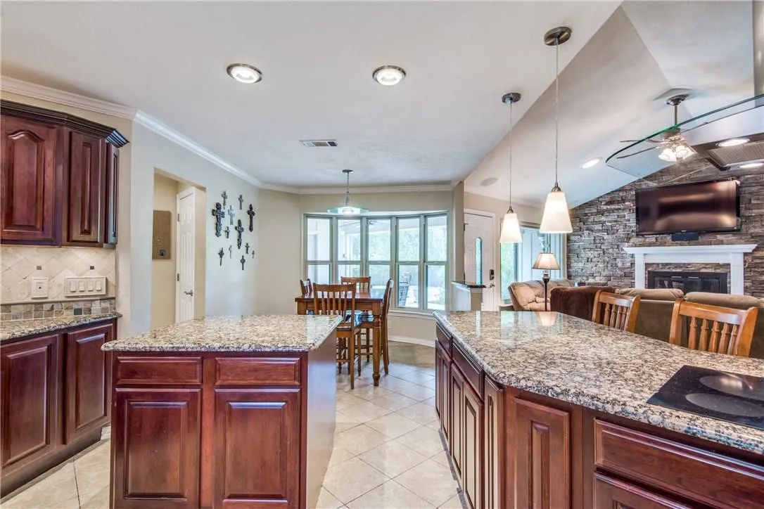 Kitchen featuring granite countertops, dark wood-finish cabinetry, recessed lighting, and pendant lighting