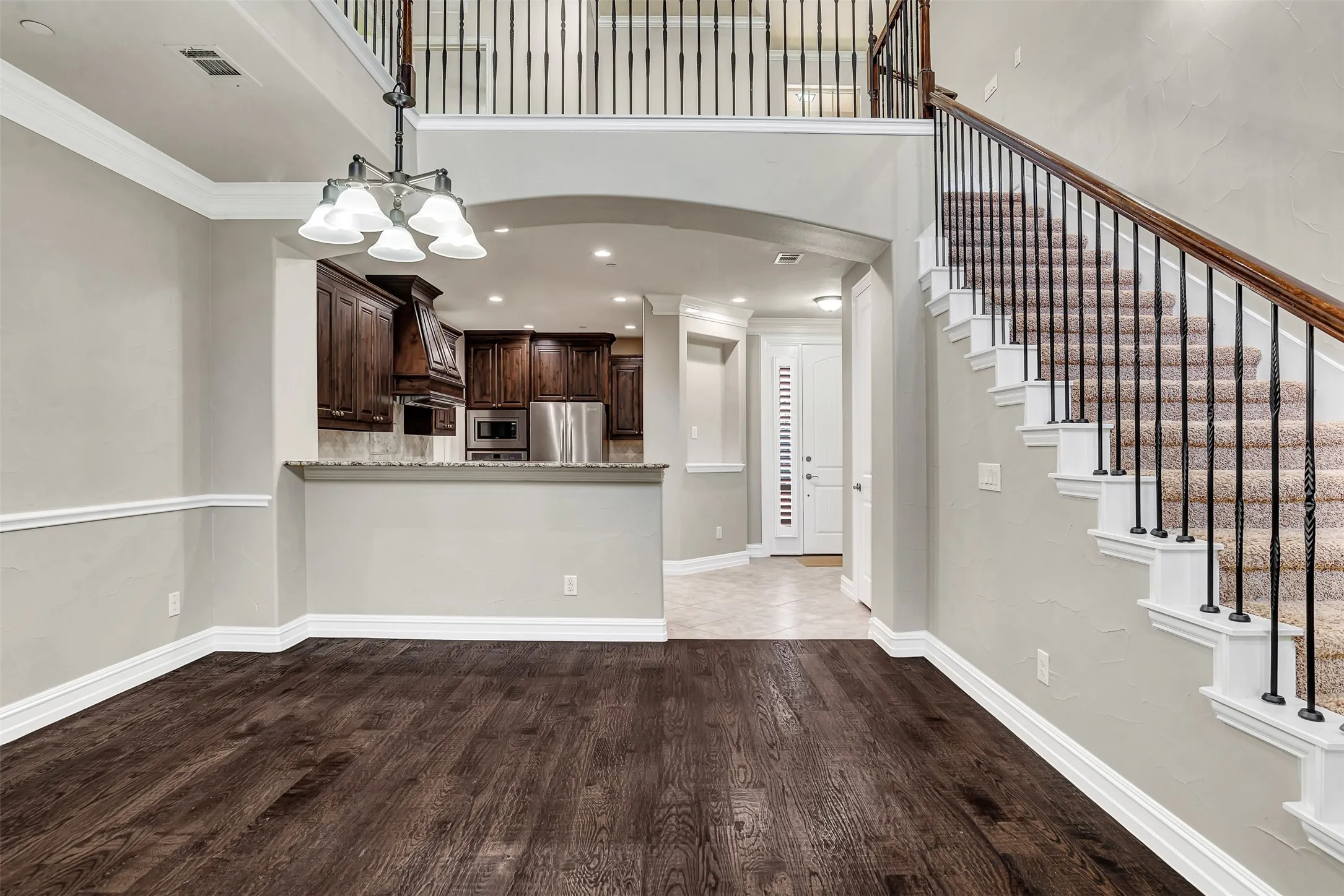 A staircase with wrought iron balusters leads to the game room and secondary bedrooms above, while keeping the home open, airy and bright! You can see how the floor plan flows from the front door to the kitchen, dining area and living room.