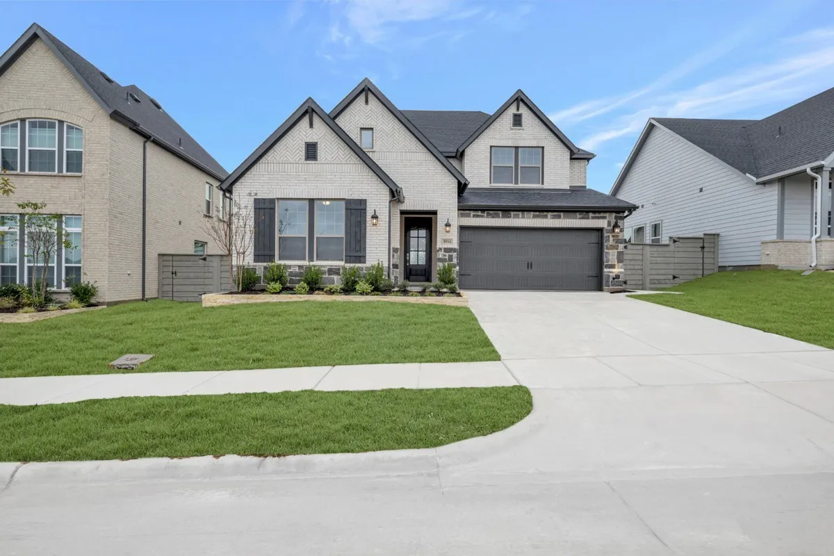 Modern two-story residence with a light-colored brick exterior, dark-trimmed gables, and a contrasting dark roof