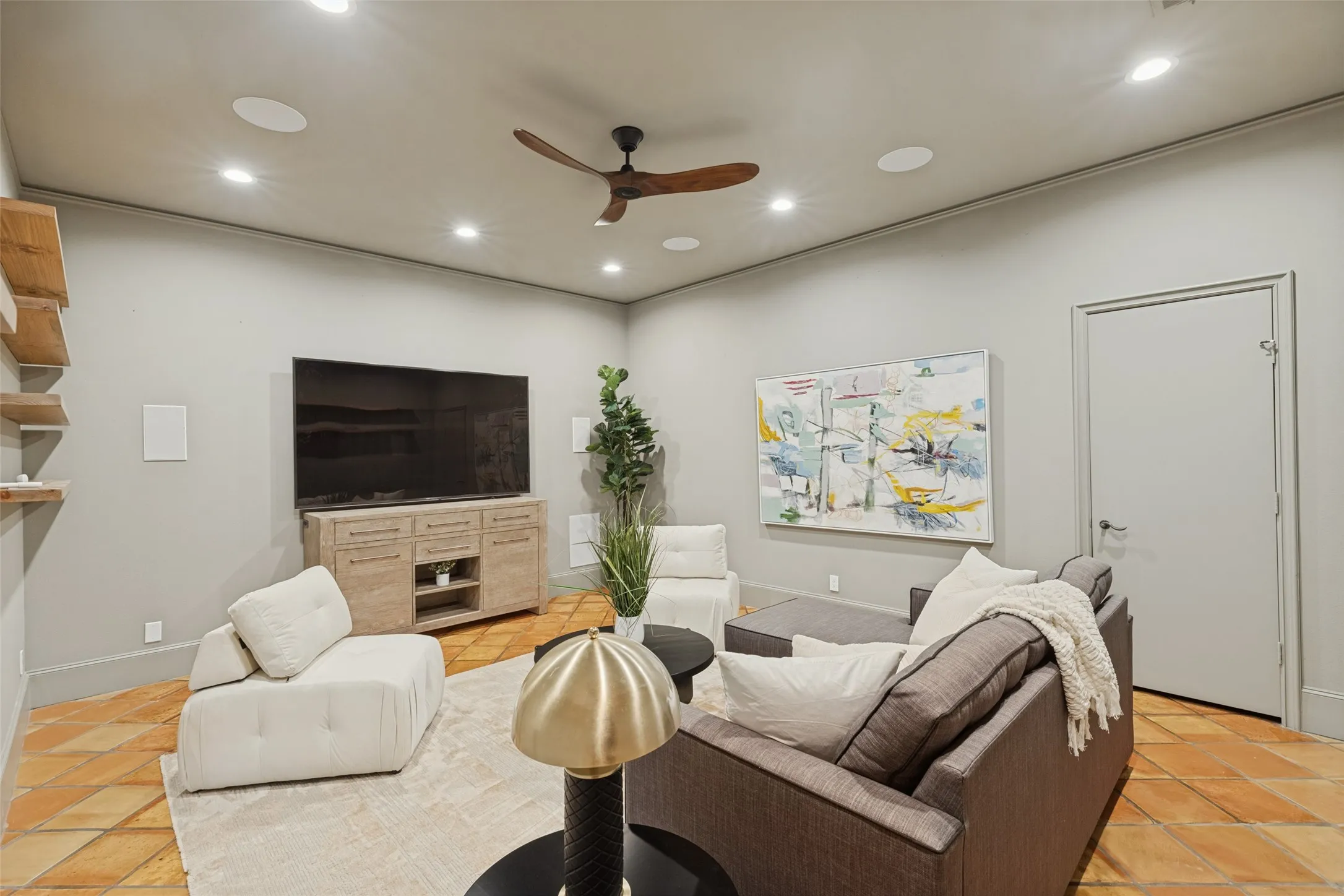 Recessed ceiling lighting, a wood-finish ceiling fan, built-in ceiling speakers, and terra cotta-style flooring