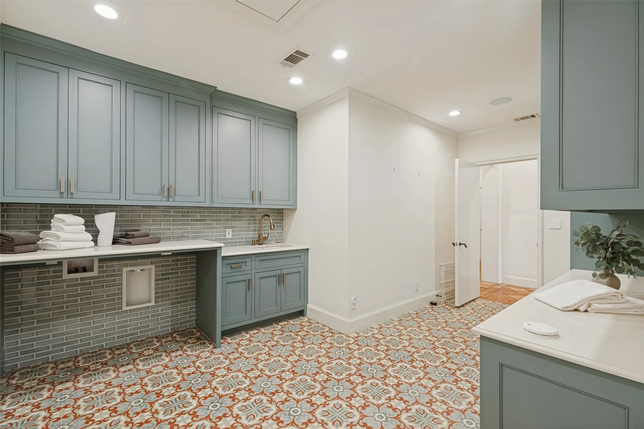 Patterned floor tile, extensive cabinetry with brushed nickel hardware, light-toned countertop, subway tile backsplash, and recessed lighting