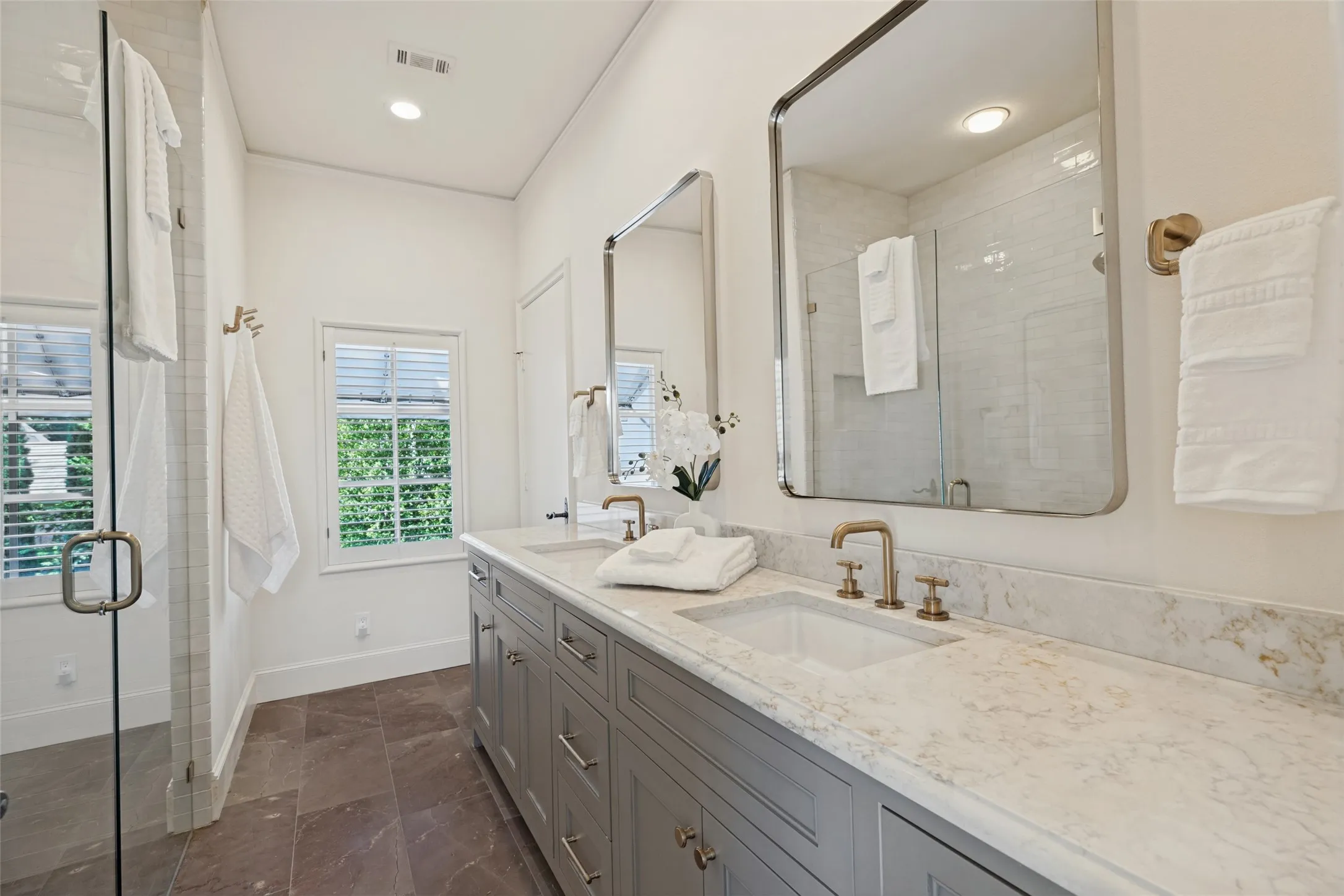 Dual vanity with a stone countertop, under-mount sinks, and brass-finish fixtures
