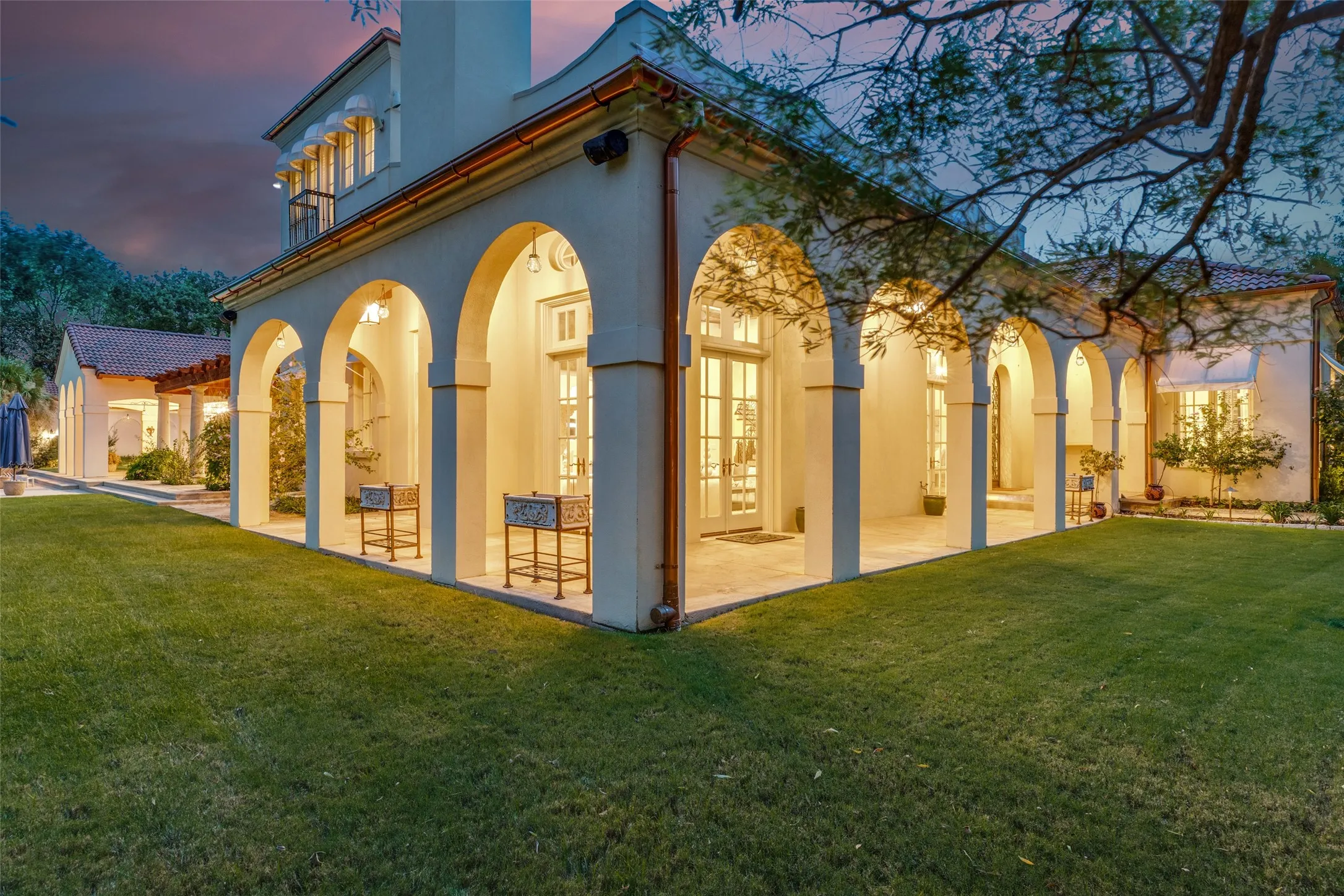 Stucco exterior with multiple arched entries, a covered patio, and a second-story balcony