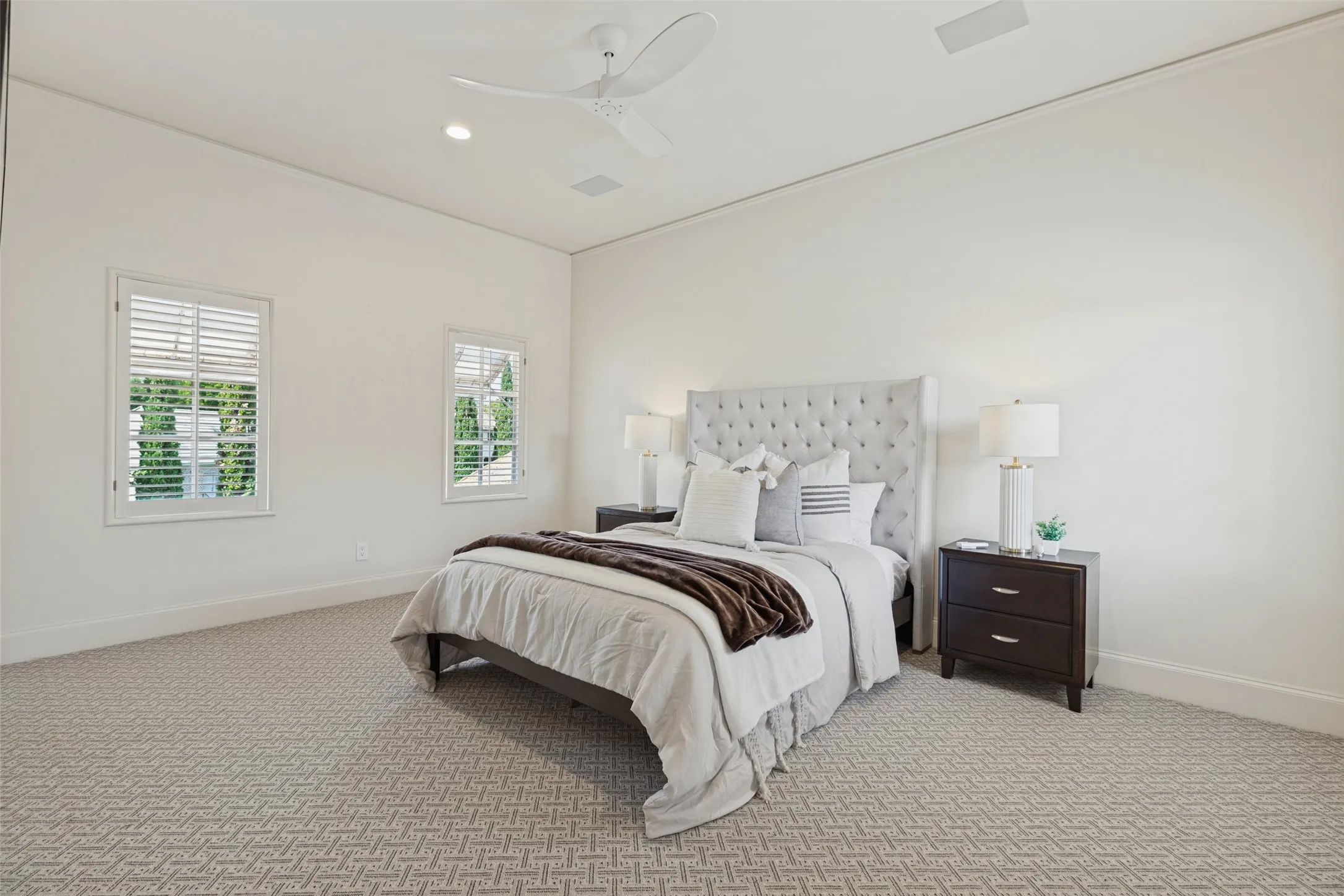 Recessed lighting, patterned carpeting, white plantation shutters, and a ceiling fan with integrated lighting