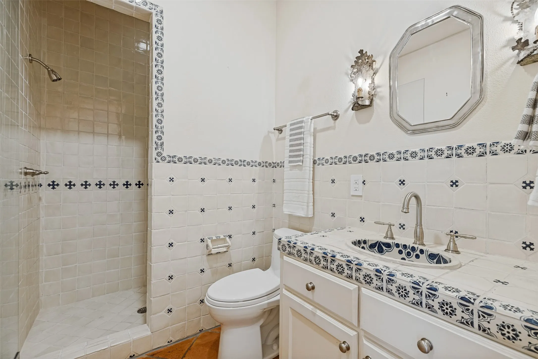 Custom tiled vanity with integrated sink, chrome fixtures, and sconce lighting