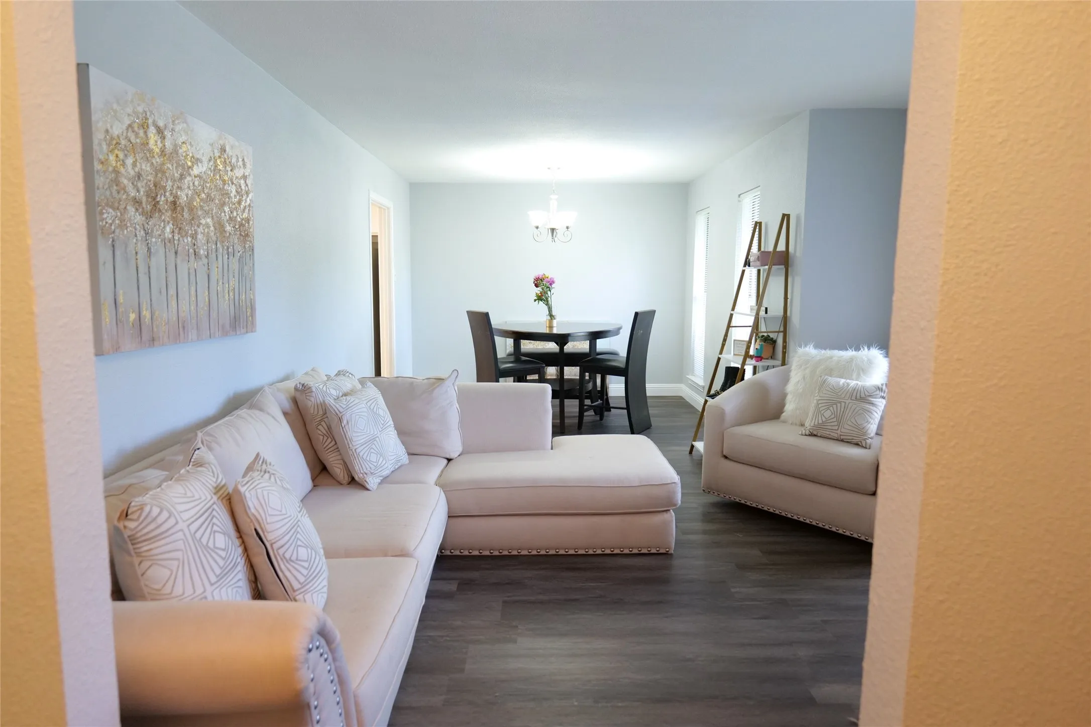 Open-concept living area with wood-finish flooring, light-toned walls, and recessed lighting