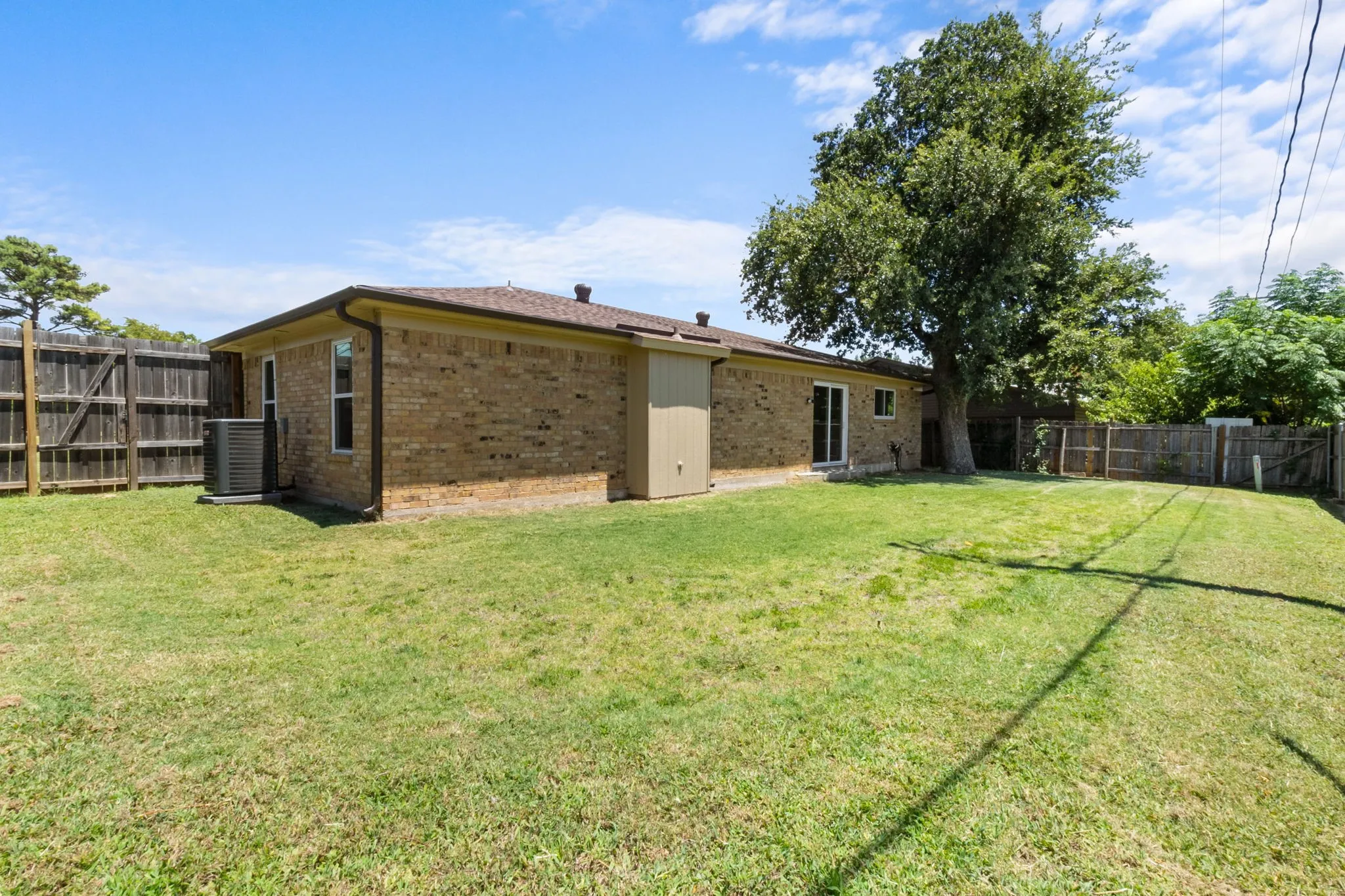 Expansive backyard featuring a manicured lawn, a mature tree, and a full privacy fence