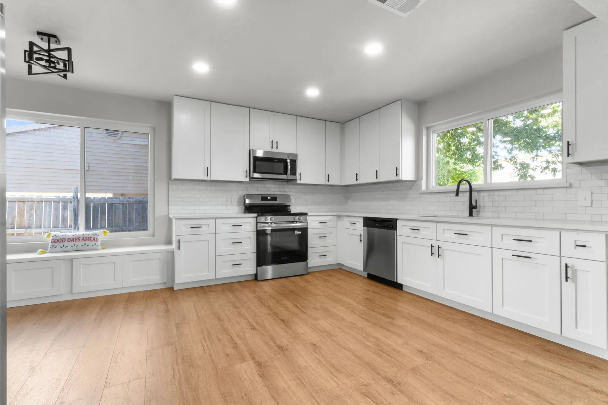 Modern kitchen featuring white cabinetry, stainless steel appliances, wood-finish flooring, subway tile backsplash, and recessed lighting