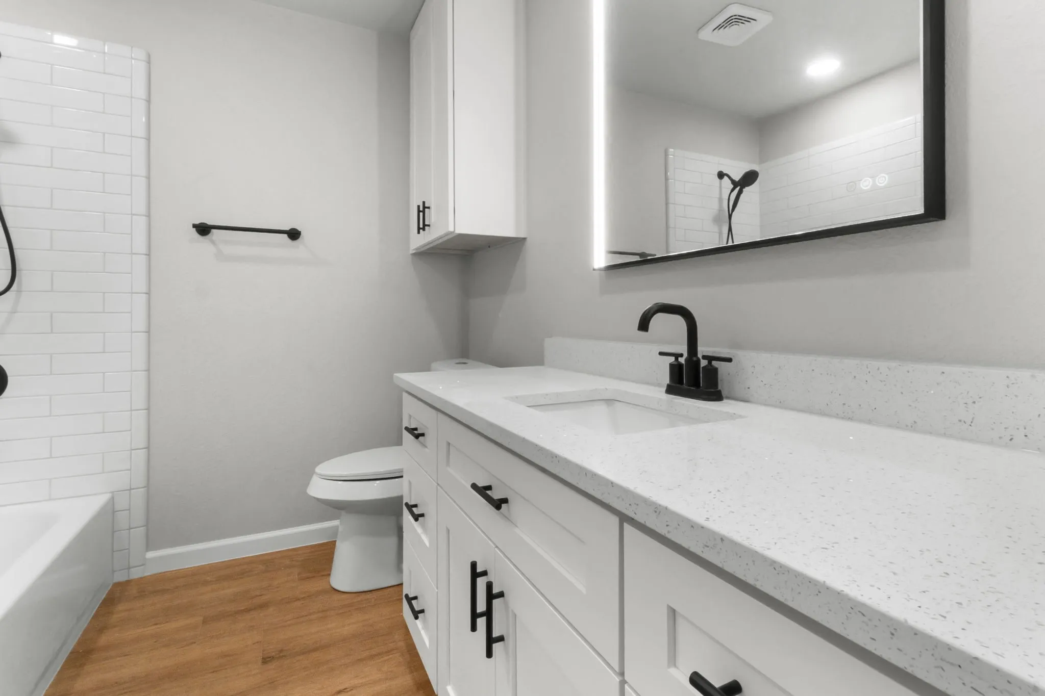 White vanity with black hardware, integrated sink, and white speckled countertop