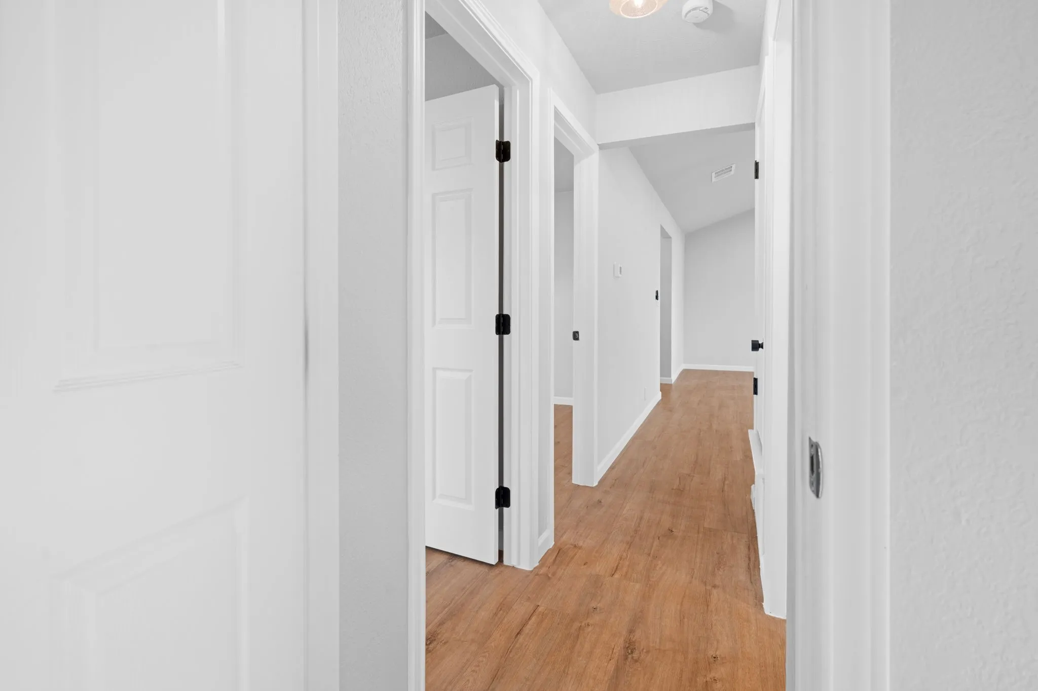Hallway featuring wood-finish flooring, white walls, and white paneled doors