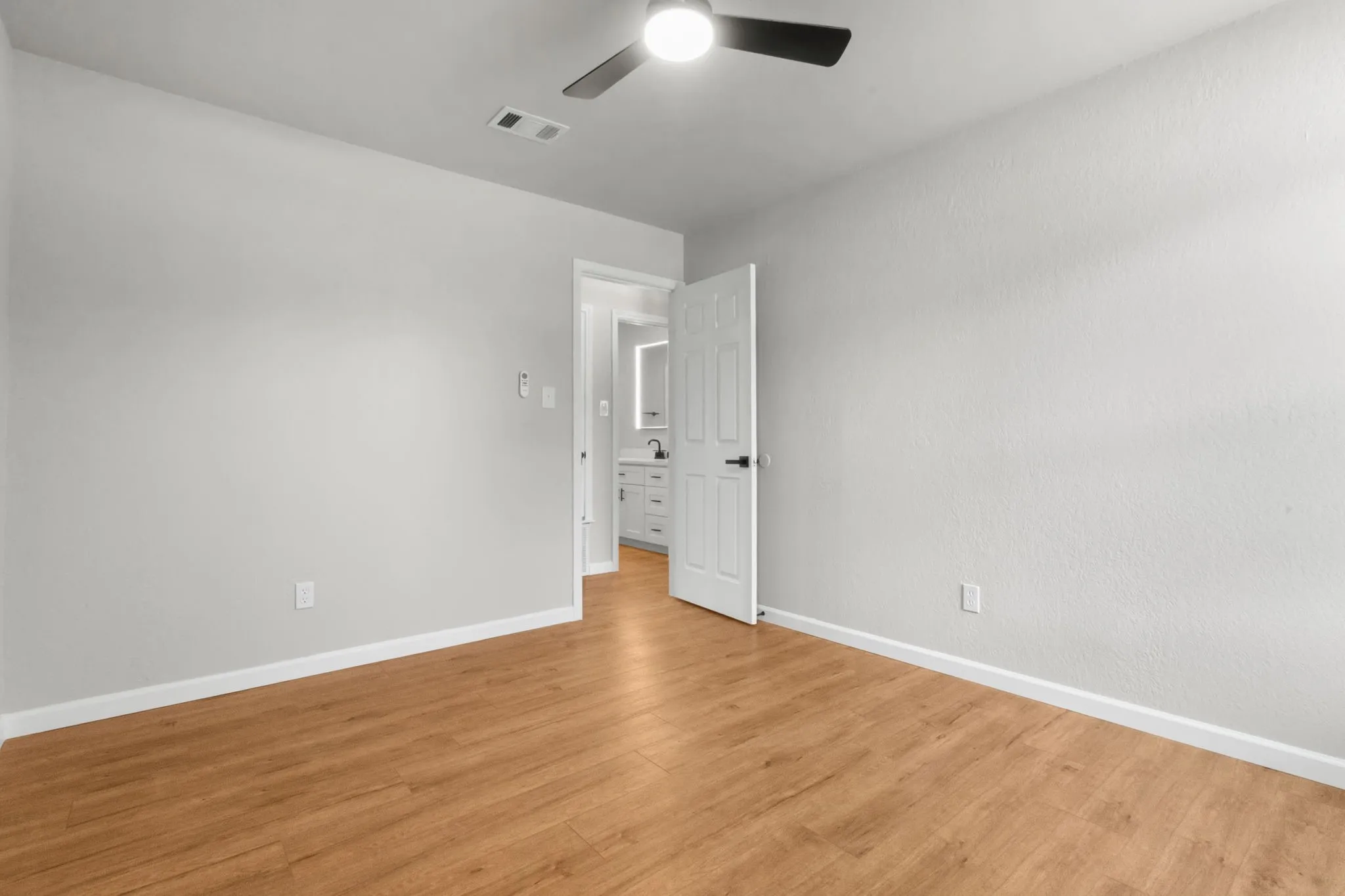 Wood-finish flooring, ceiling fan, and white painted walls
