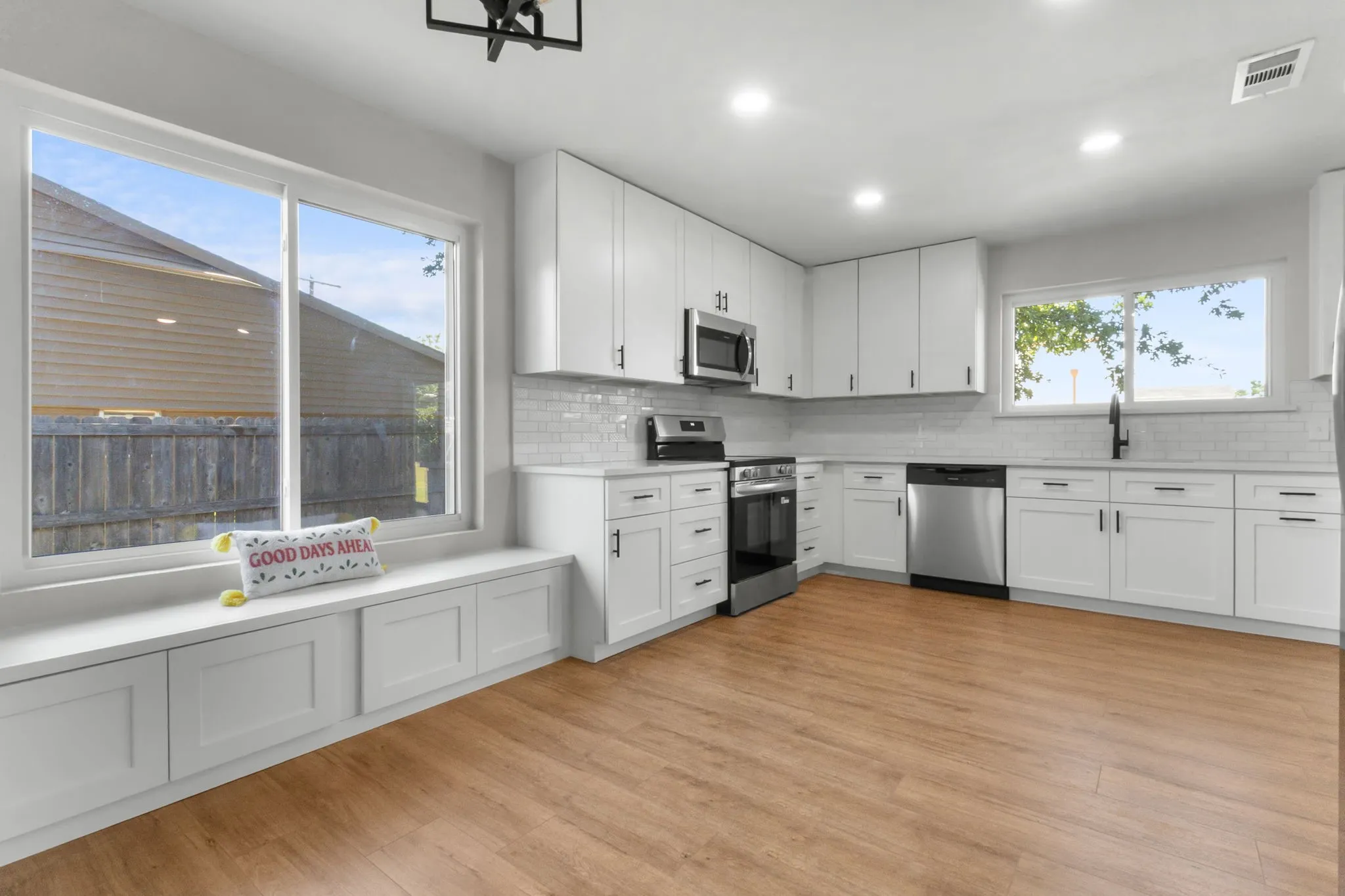 Well-appointed kitchen featuring white cabinetry, stainless steel appliances, wood-finish flooring, a white subway tile backsplash, and recessed lighting