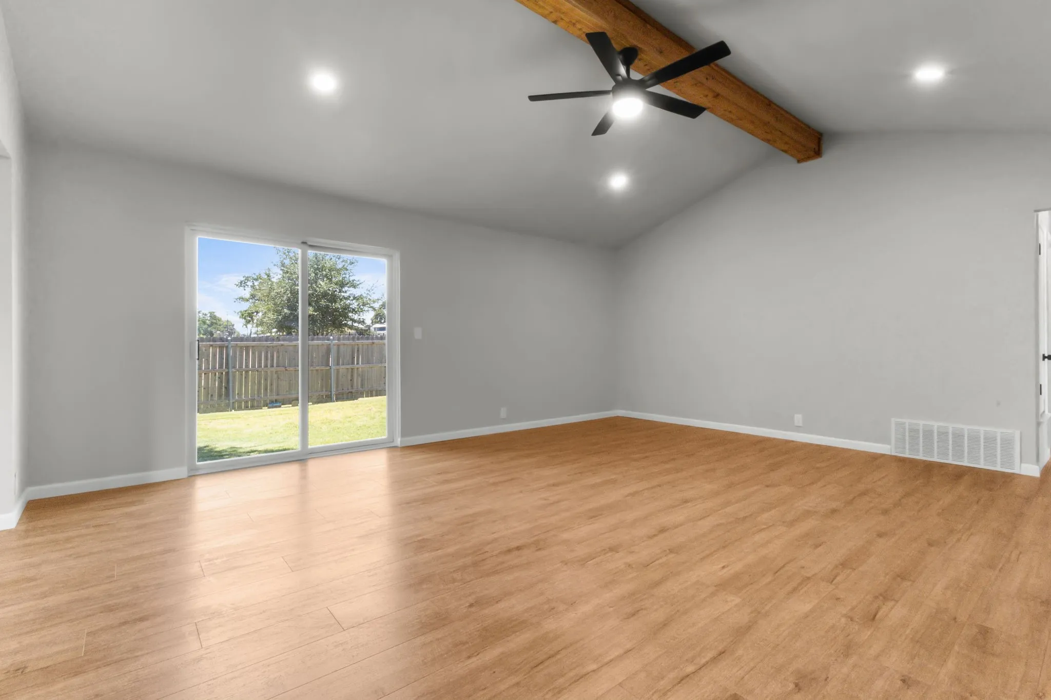 Vaulted ceiling with an exposed wood beam, wood-finish flooring, sliding glass door, recessed lighting, and a ceiling fan