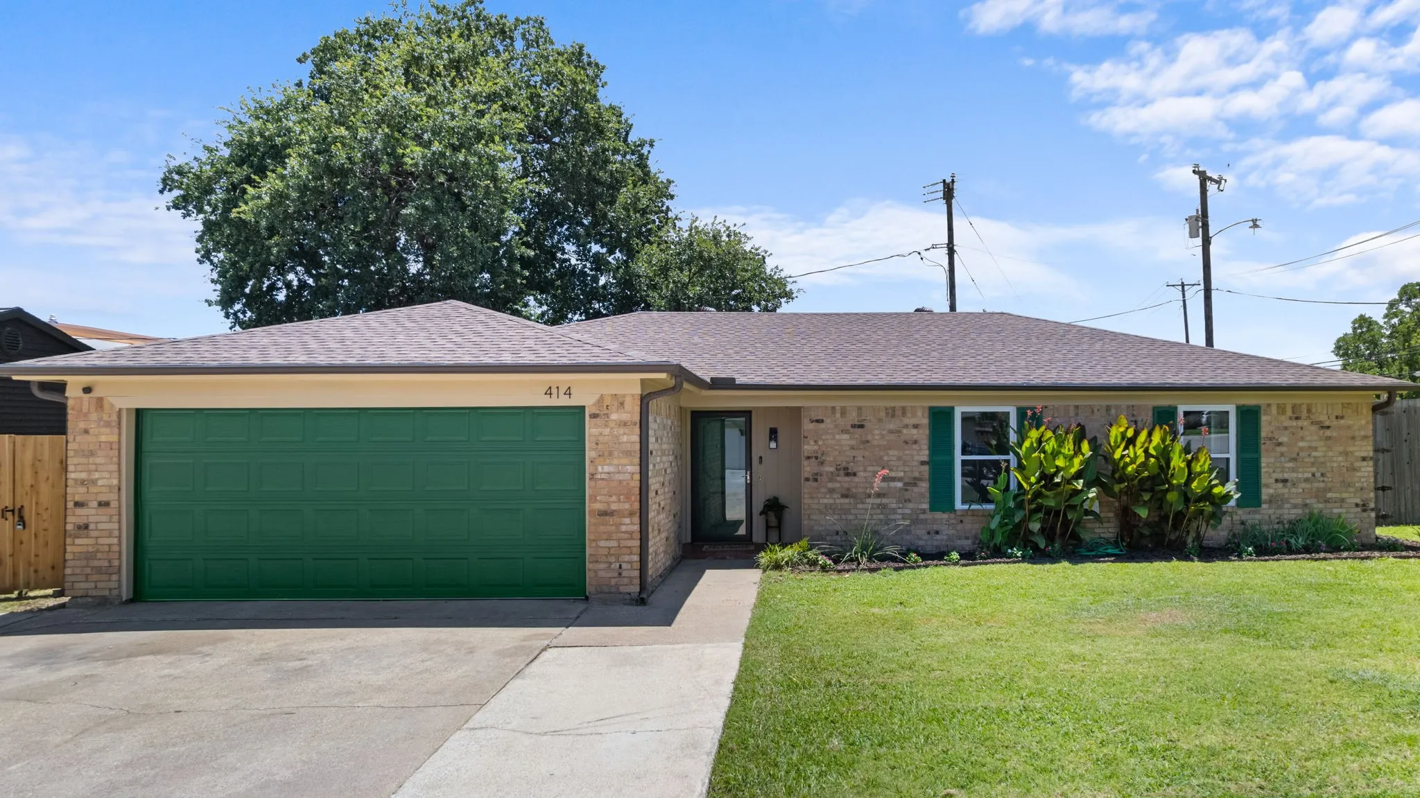 Brick exterior with a two-car garage, concrete driveway, and established landscaping