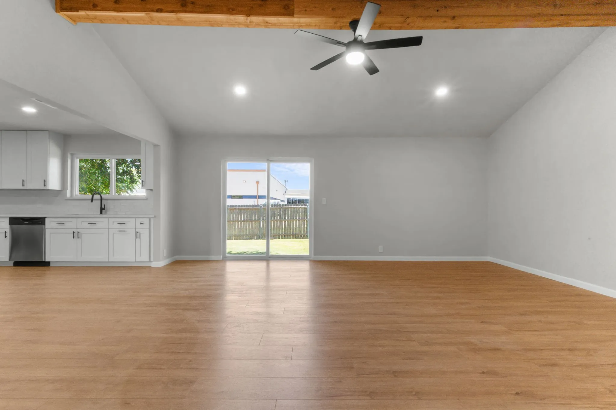 Vaulted ceiling with exposed wood beam, wood-finish flooring, and recessed lighting