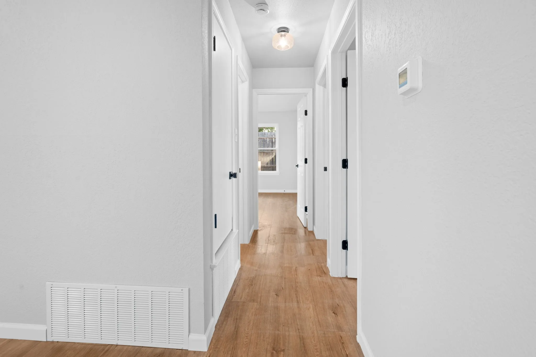 Hallway featuring wood-finish flooring, white walls, and white trim