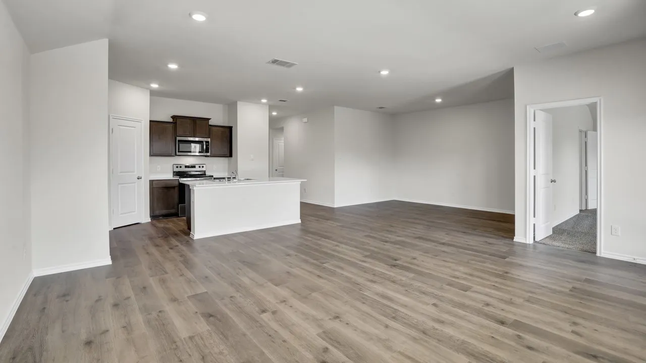 Open-concept living space featuring wood-finish flooring, recessed lighting, and a kitchen island with integrated sink