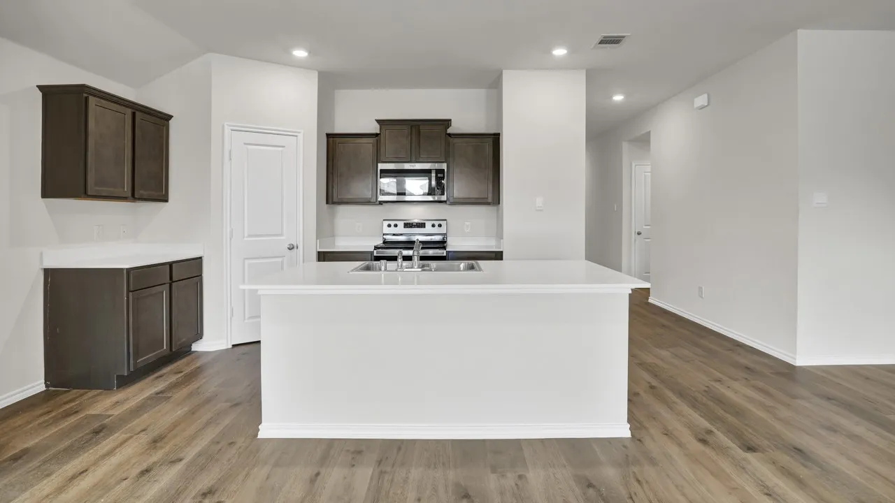 Kitchen featuring wood-finish flooring, recessed lighting, dark wood cabinetry, stainless steel appliances, and a central island with a white countertop