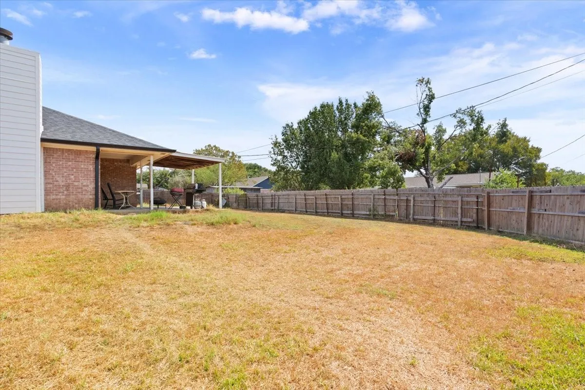 Expansive backyard featuring a wood fence perimeter and a covered concrete patio