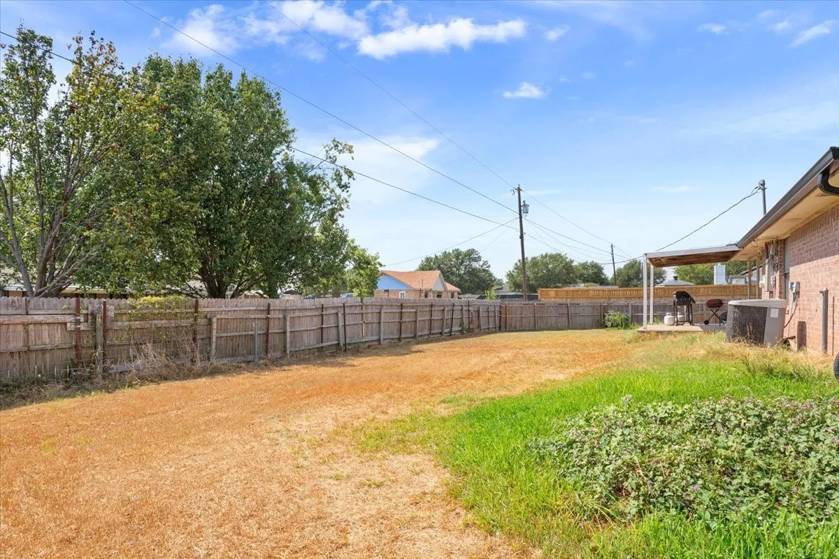 Expansive rear yard featuring a wood privacy fence and a covered patio area