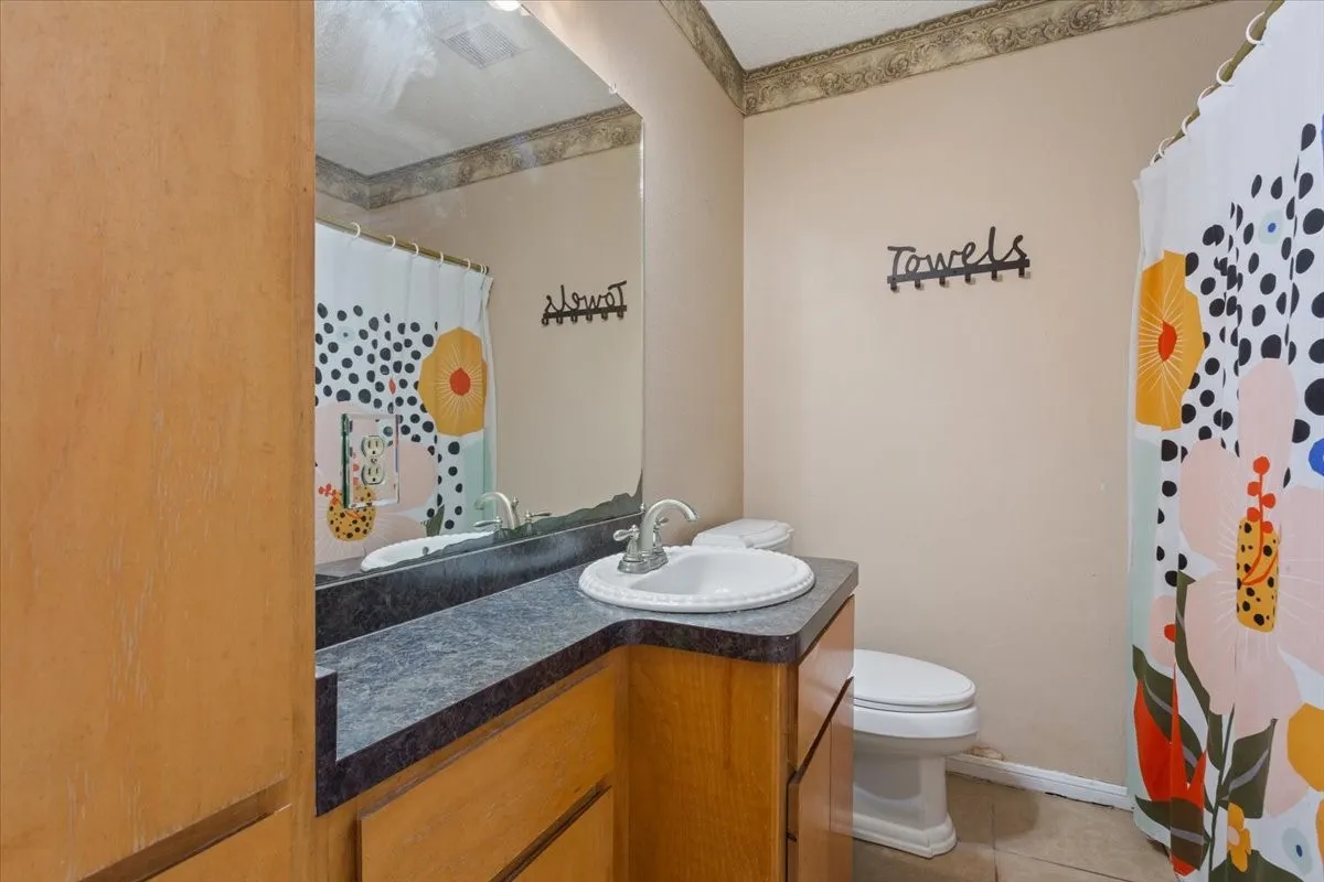 Vanity with integrated sink, dark countertop, and wood-finish cabinetry