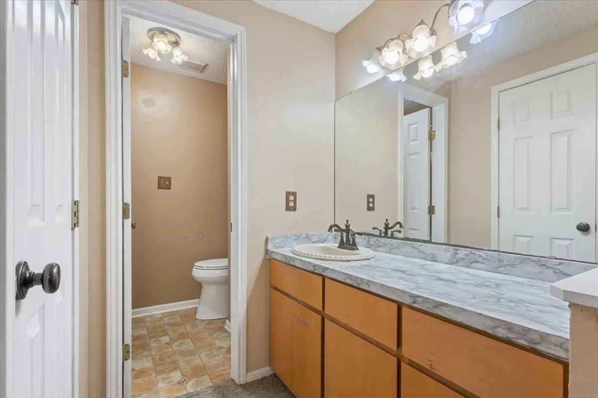 Extended vanity with a light-colored countertop, integrated sink, and bronze-finish faucet