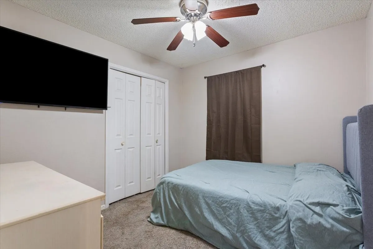 Ceiling fan with wood-finish blades, bi-fold closet doors, wall-to-wall carpeting