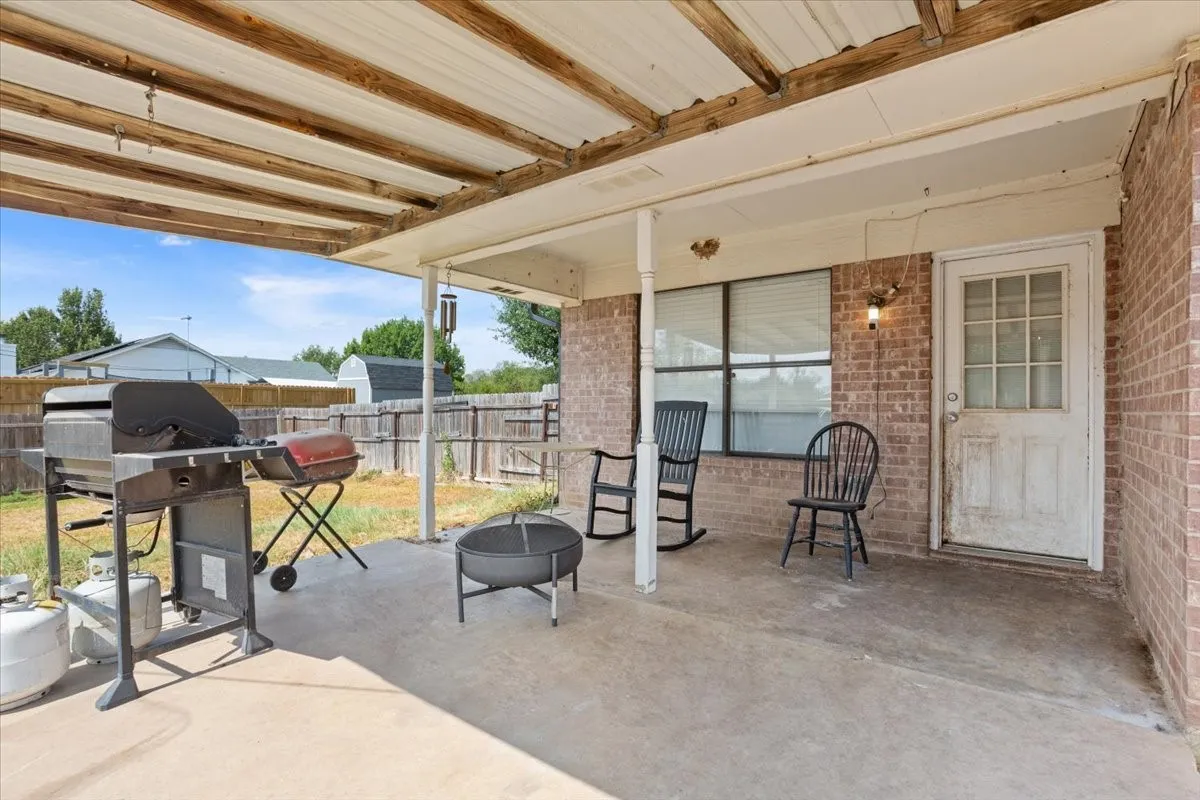 Covered patio with a concrete surface, brick exterior, and wood-paneled ceiling