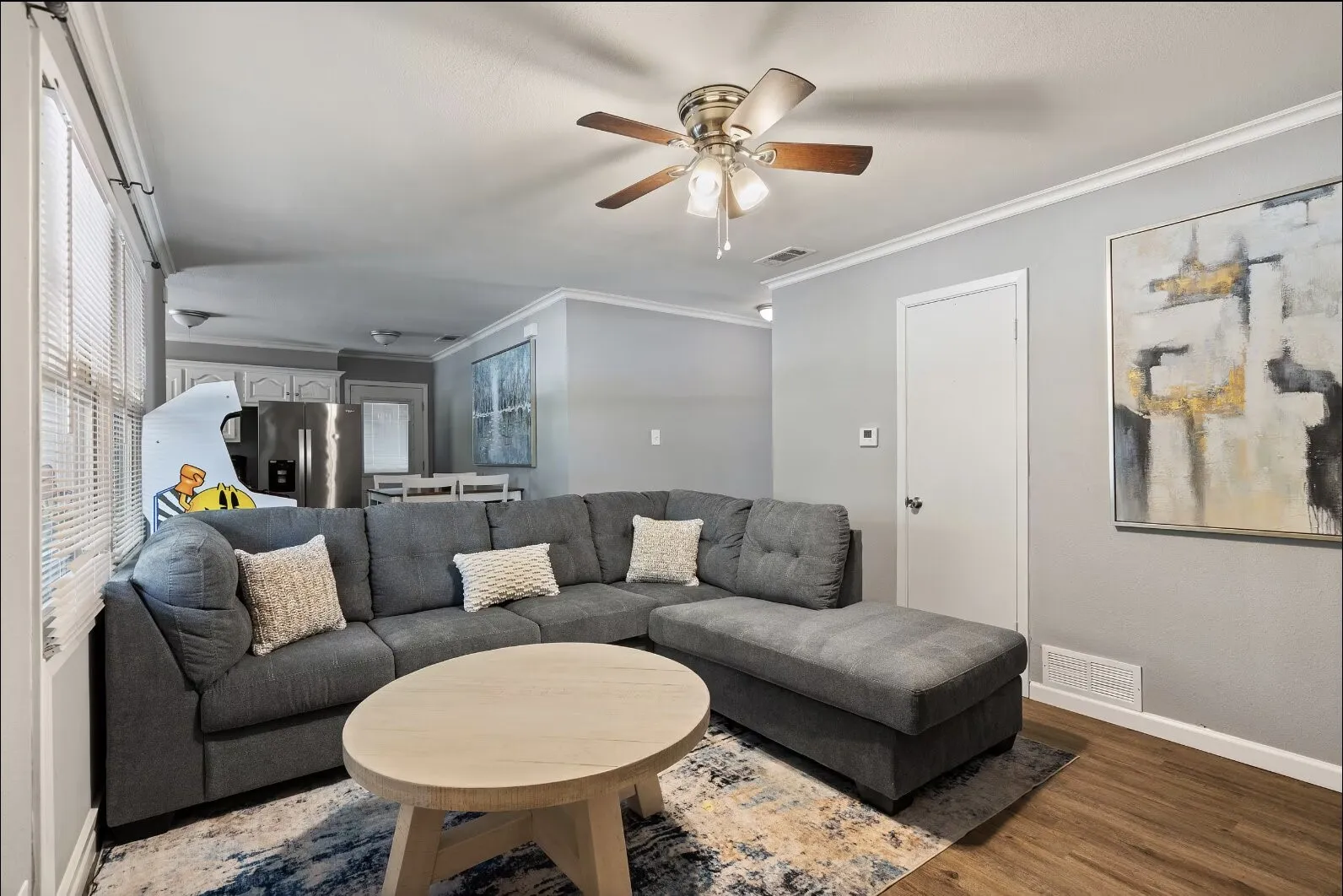 Living area featuring wood-finish flooring, ceiling fan, and crown molding