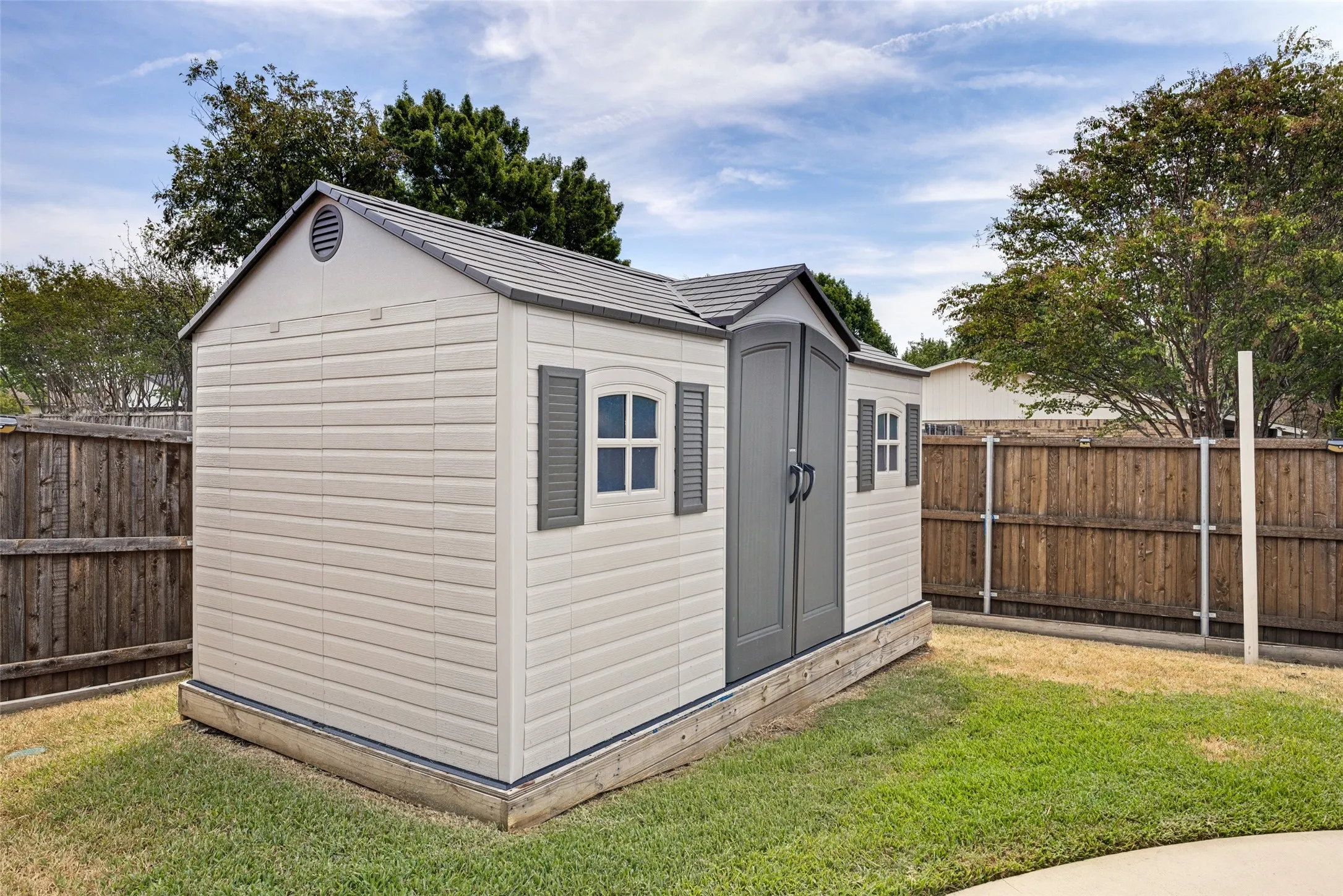Outdoor storage shed with a gabled roof, double doors, and decorative windows