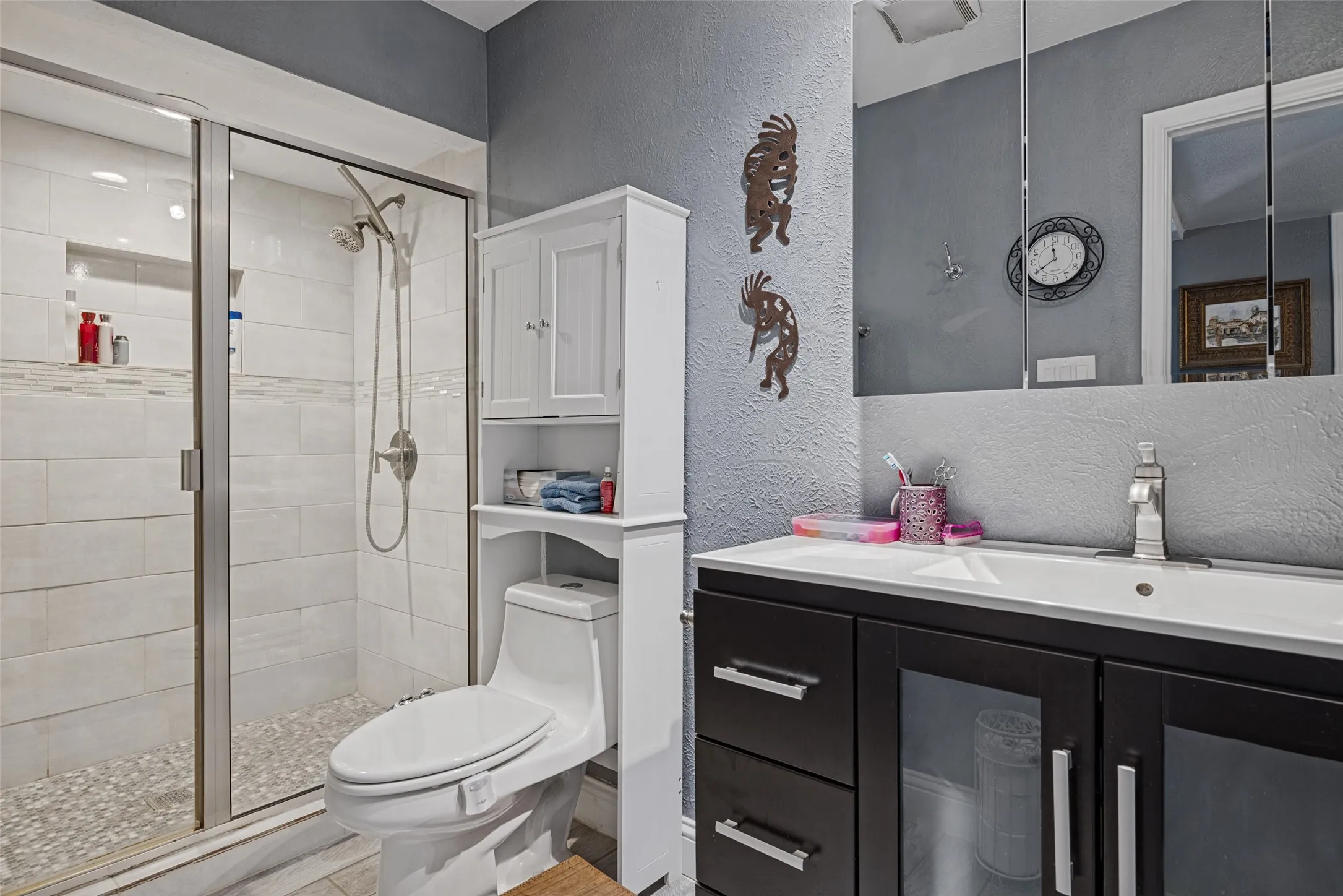 Glass-enclosed shower with tiled walls and pebble floor