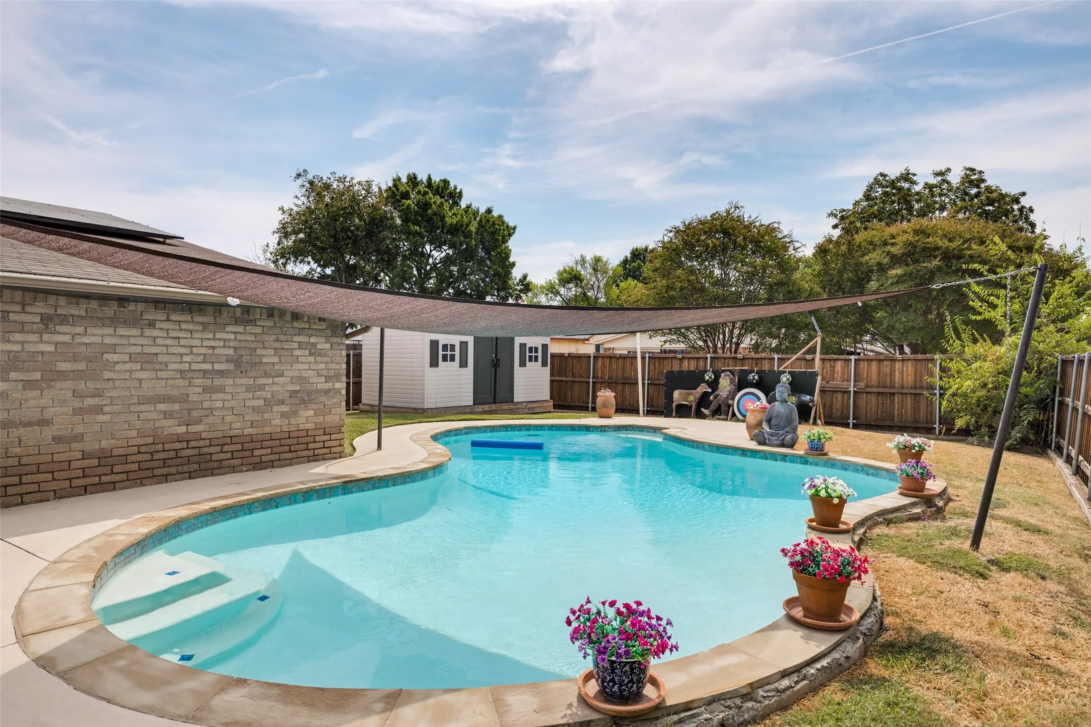 Freeform swimming pool with integrated steps, surrounded by a concrete patio and stone coping