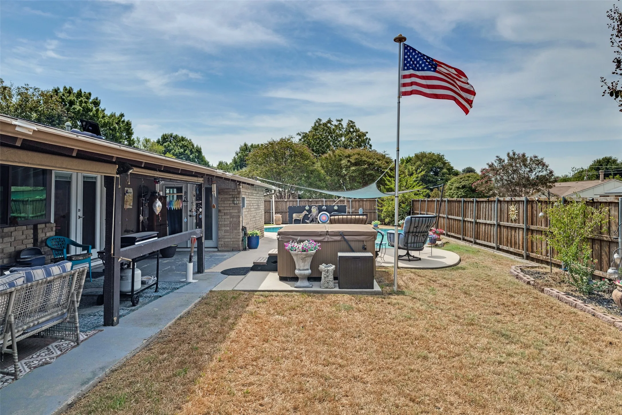 Expansive backyard featuring a hot tub, concrete patio, and a wood privacy fence