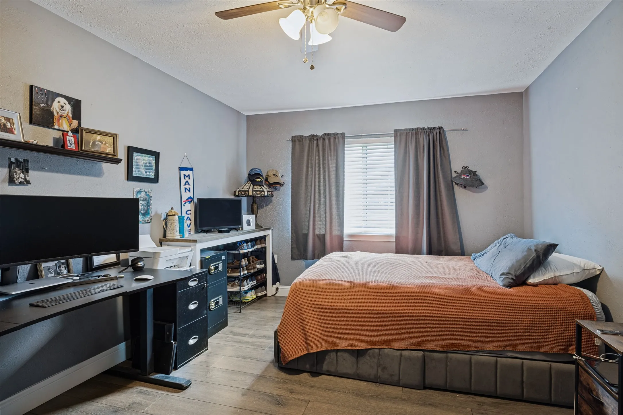 Room featuring a ceiling fan with integrated lighting, wood-finish flooring, and a window with blinds