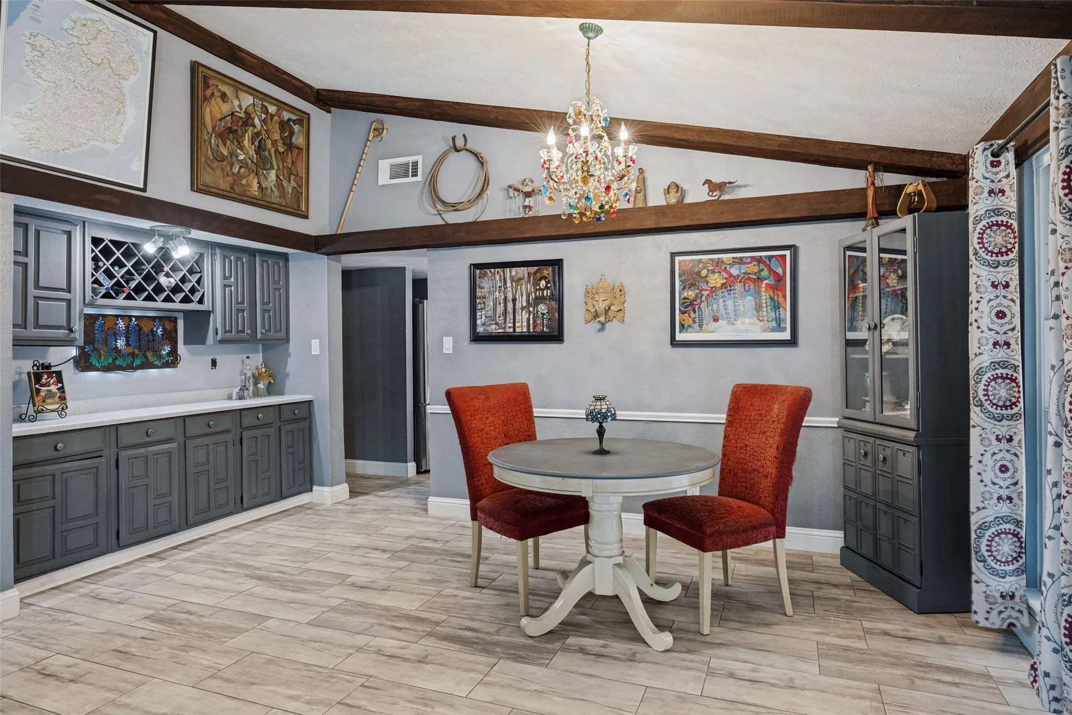 Wood-finish flooring, exposed ceiling beams, built-in cabinetry with wine storage, white countertops, and a decorative chandelier