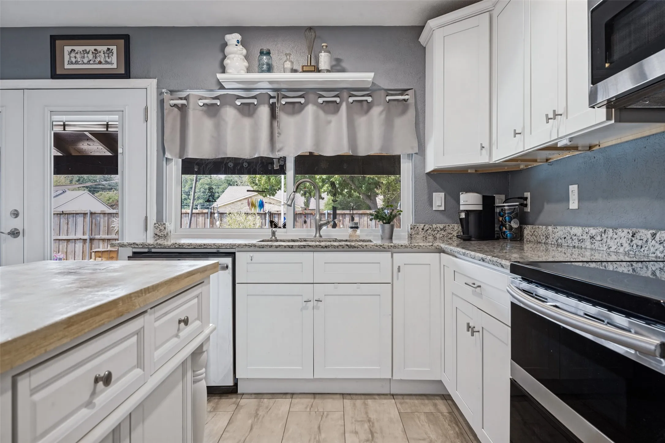 White cabinetry with brushed nickel hardware, granite countertops, stainless steel appliances, wood-finish flooring, and a central island with a wood-finish top