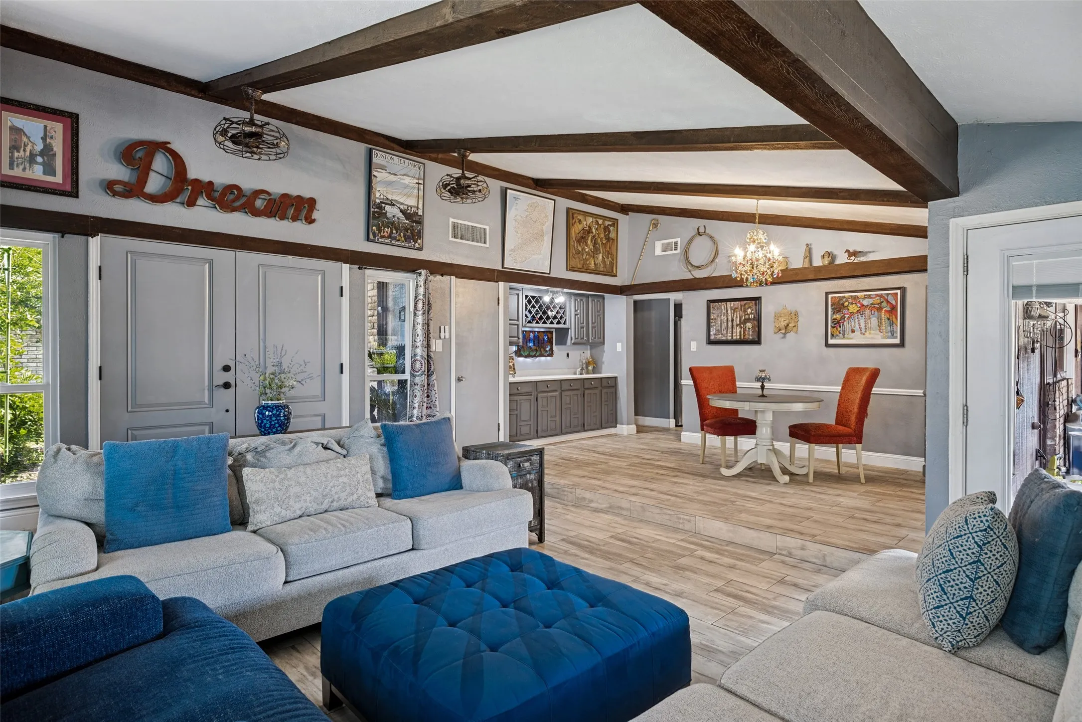 Exposed wood beams, wood-finish flooring, built-in cabinetry, and a crystal chandelier