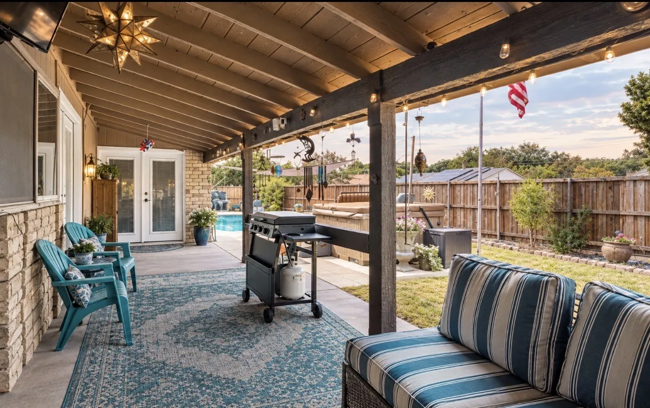 Covered patio with a wood-finish ceiling, brick facade, and string lights
