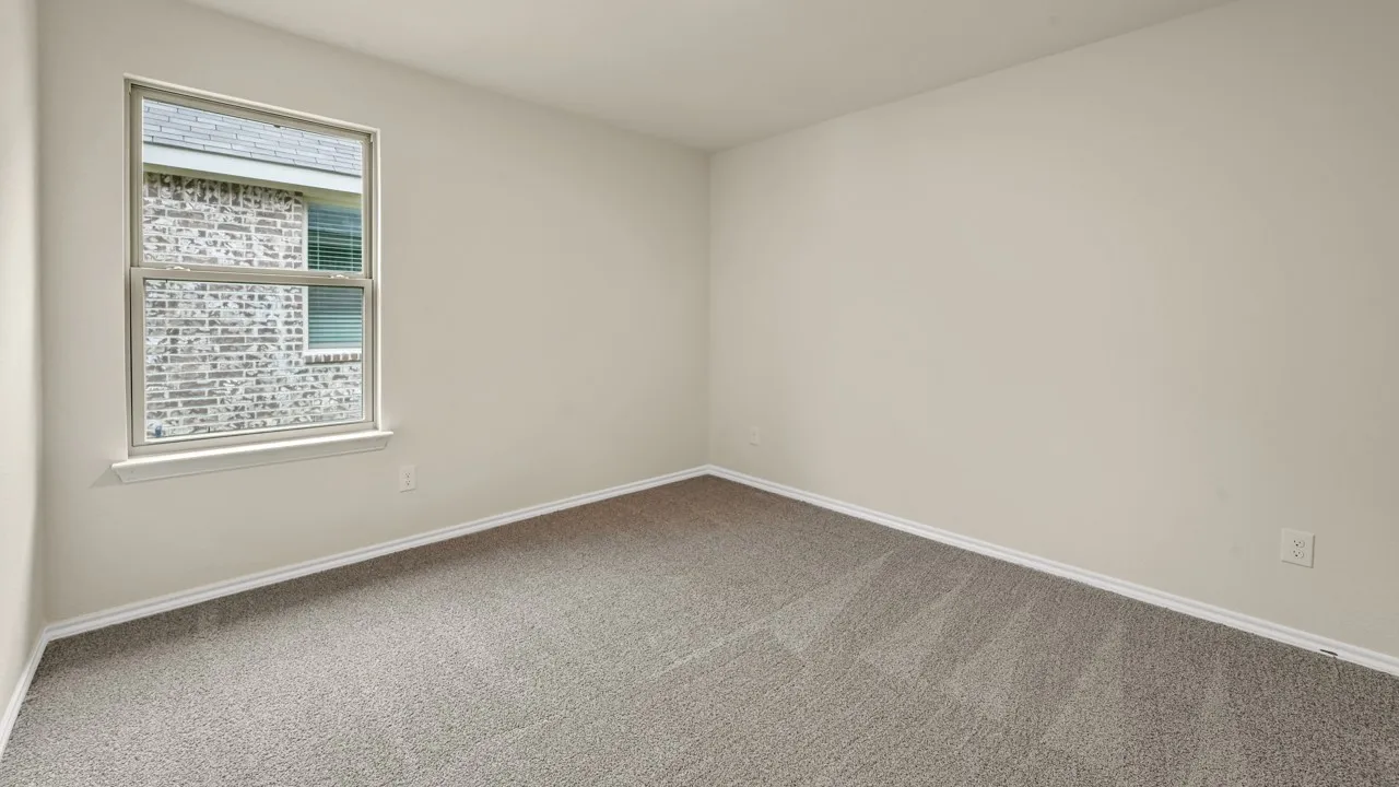 Neutral wall paint, gray carpet flooring, and a double-hung window