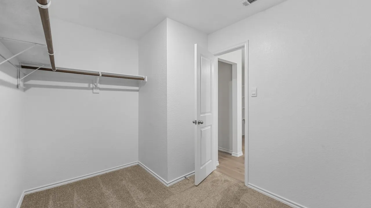 Carpeted room with a built-in closet rod and shelving