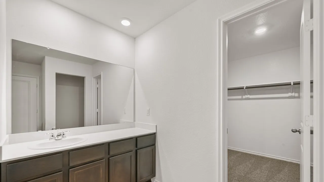 Bathroom vanity with single basin sink, white countertop, dark wood-finish cabinetry, and an expansive wall-mounted mirror