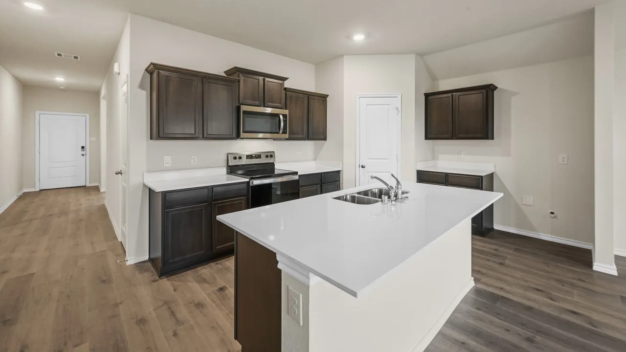 Kitchen featuring a central island with a double basin sink, stainless steel appliances, dark wood-finish cabinetry, light countertops, and wood-finish flooring