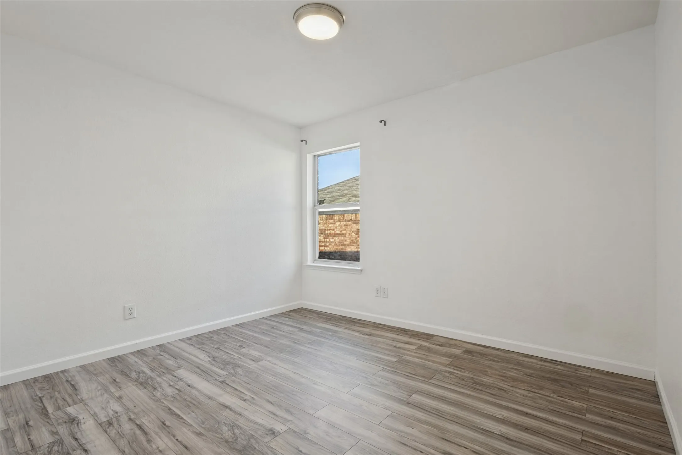 Neutral wall tones with a single window and wood-finish flooring
