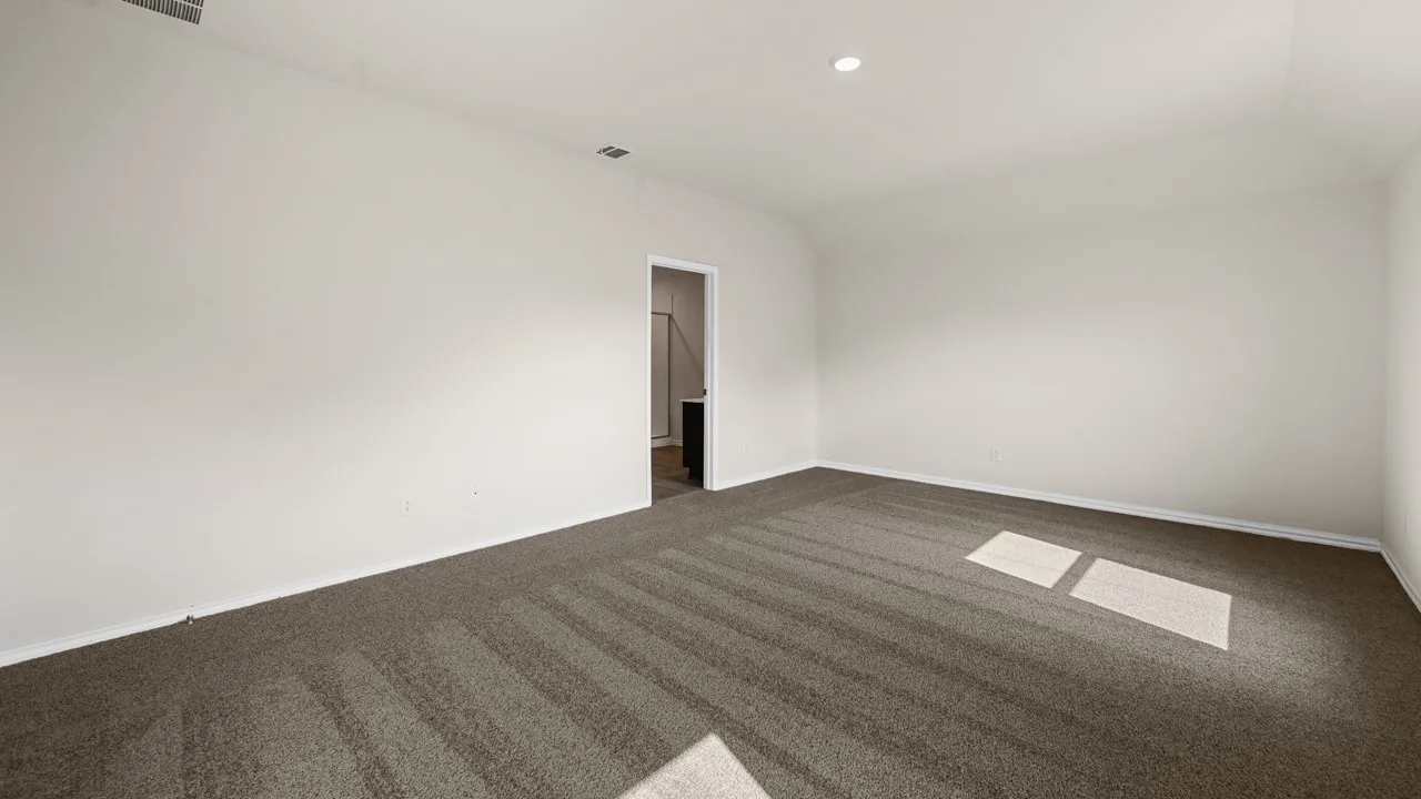 Spacious room with plush carpet flooring and a recessed ceiling light