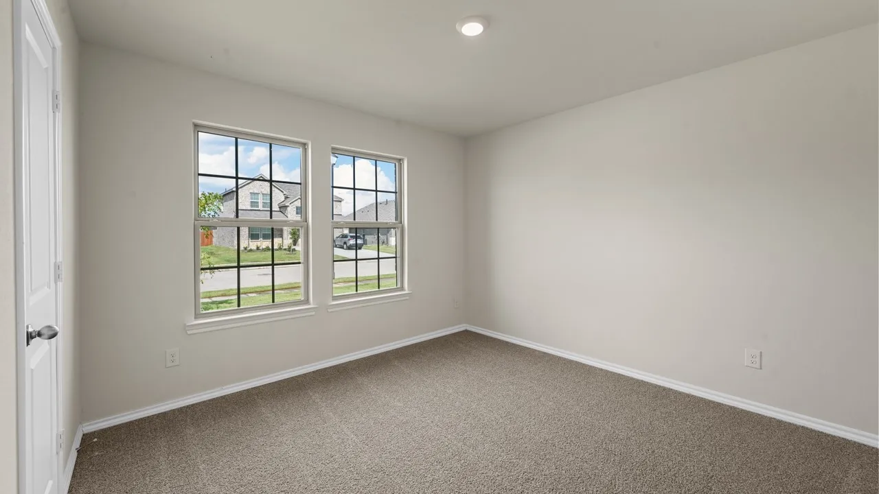 Recessed ceiling lighting illuminates a room with neutral-toned walls and carpet flooring
