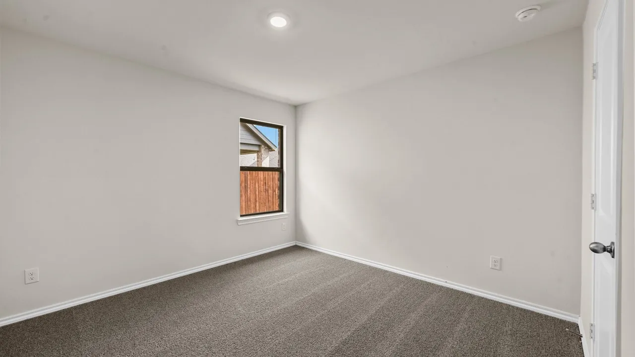Wall-to-wall carpeting, single window with exterior wood fencing, recessed lighting, and a paneled door with a round knob